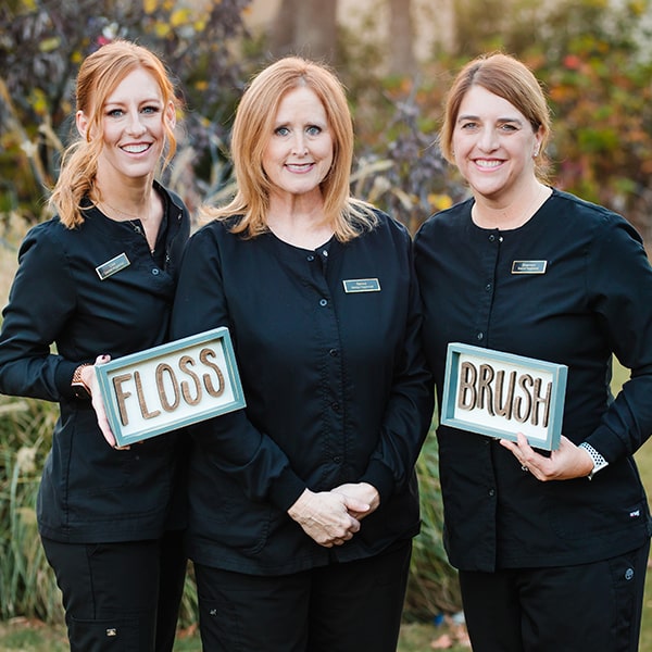 Our team of hygienists smiling while holding a sign