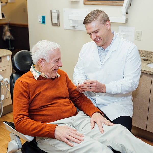 Dr. Egger explaining partial dentures to an older man in the dentist's chair