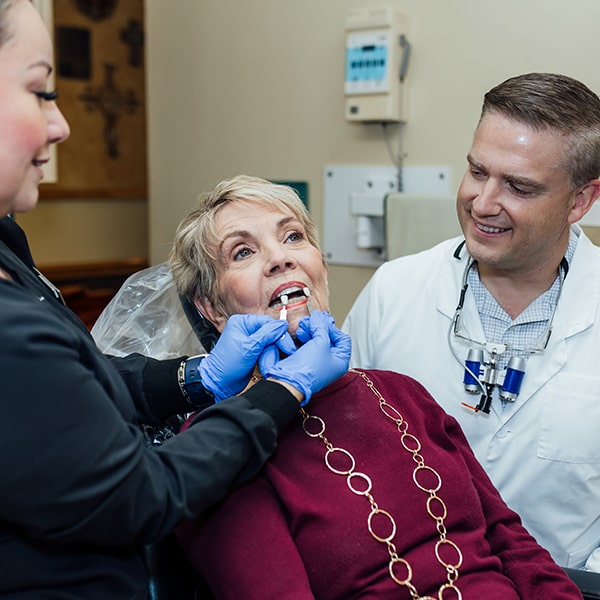 Dr. Graham and one of our assistants trying porcelain veneers on a woman in the dentist's chair