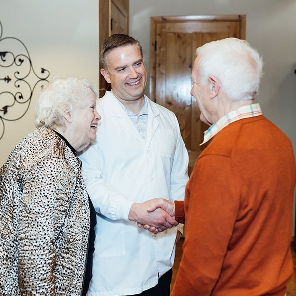 Dr. Egger greeting an elderly couple after their restorative treatment