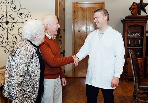 Dr. Graham Egger greeting an elderly couple as they enter the dental office